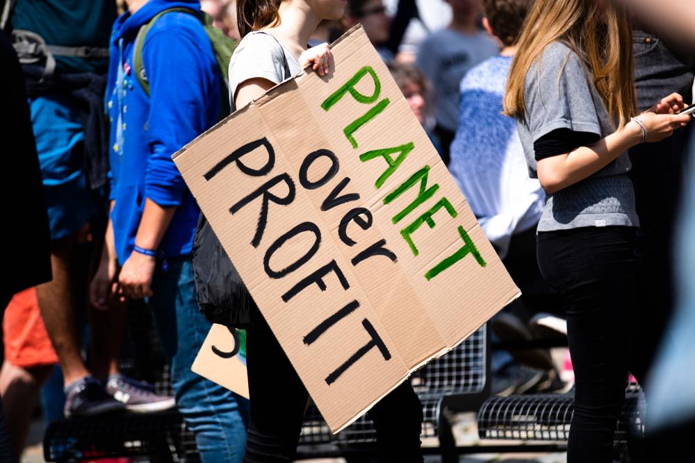 Climate change protest sign that says Planet Over Profit