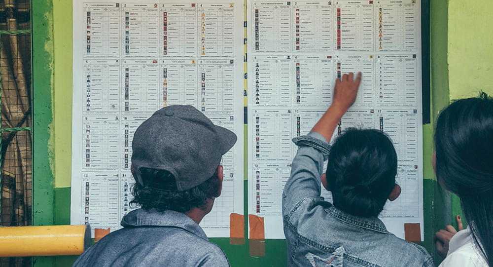Three people look at list of voting candidates 