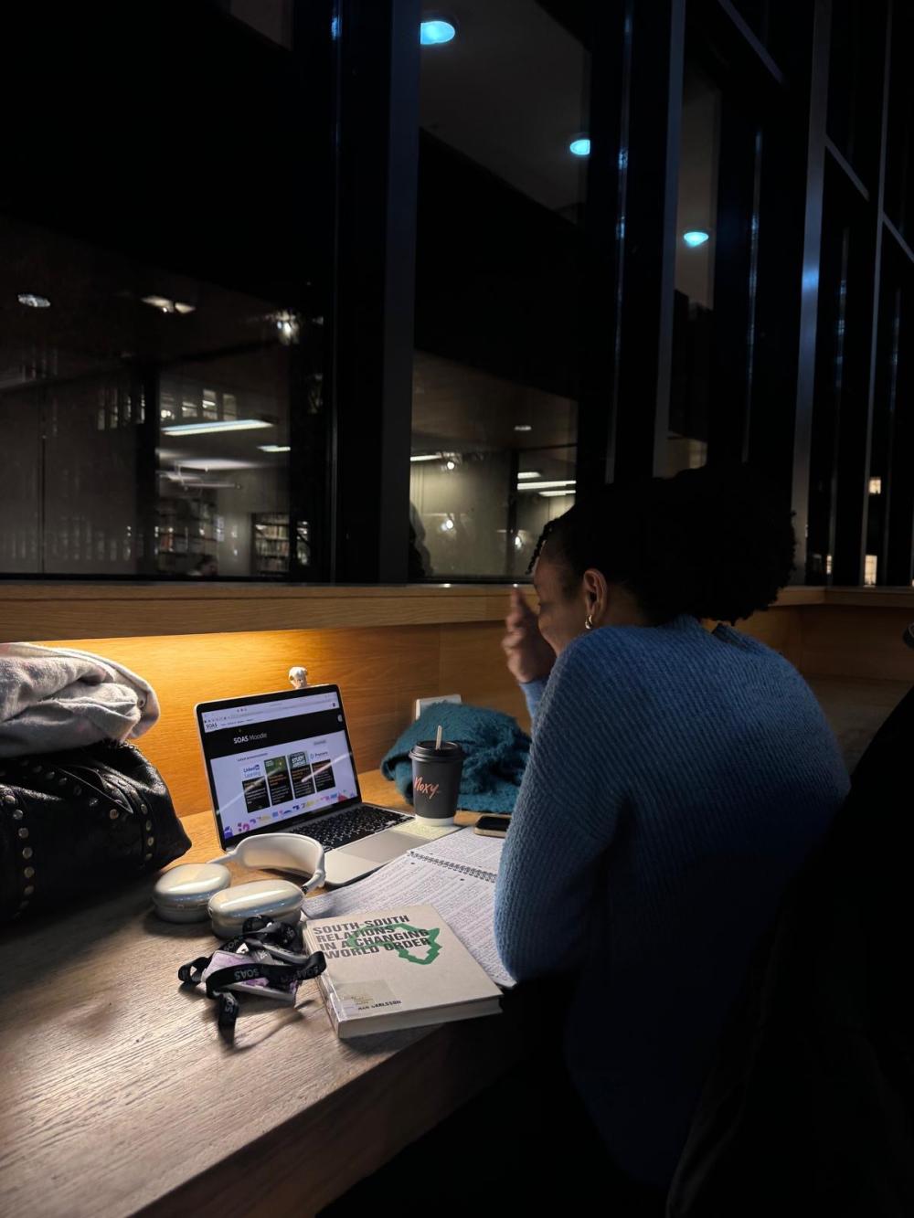 A student sits at a desk in the library laughing