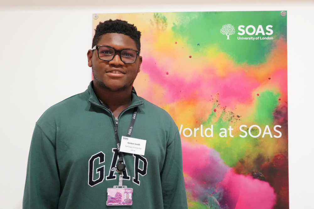 Keshon Smith stands in front of a colourful SOAS sign