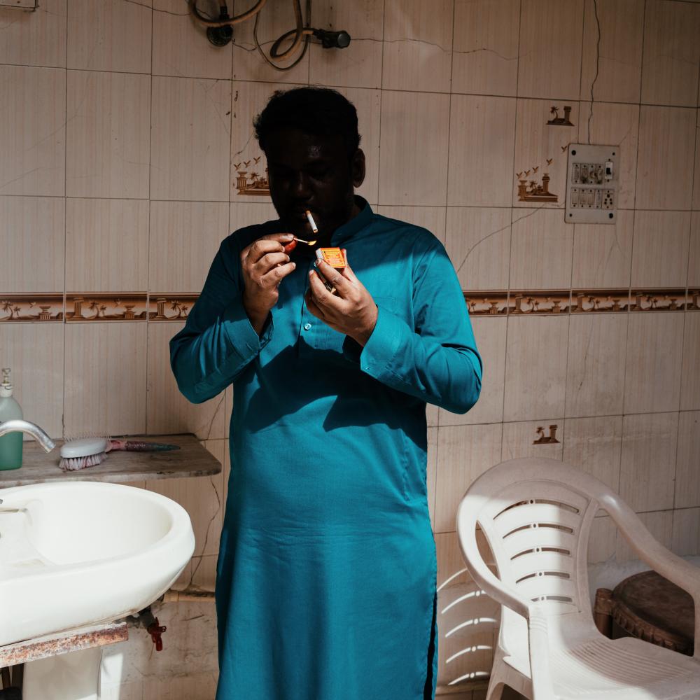 photograph from Batul exhibition of a man in shadows, smoking a cigarette